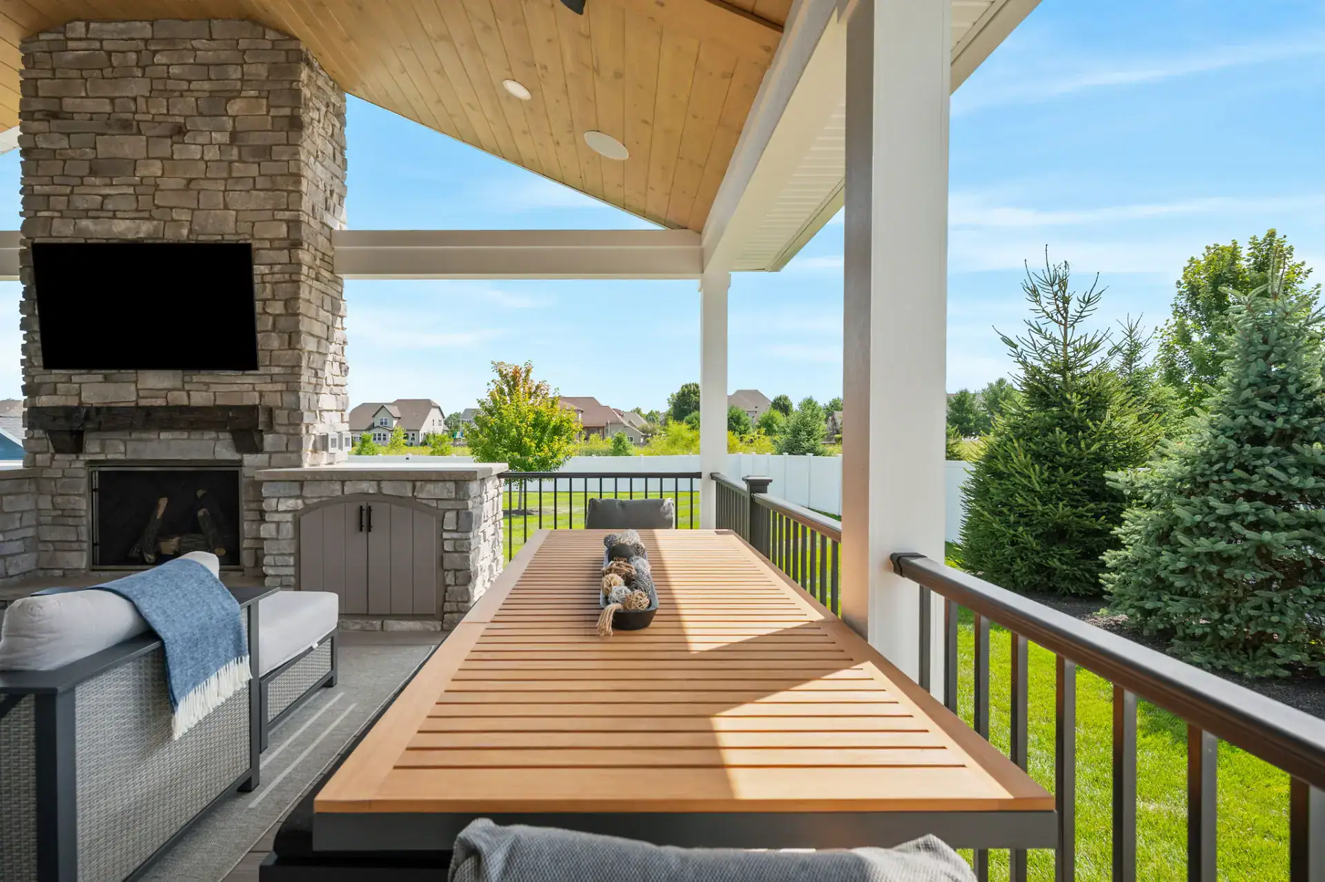 Covered porch dining area with outdoor fireplace in Medina, Ohio by TAB Property Enhancement