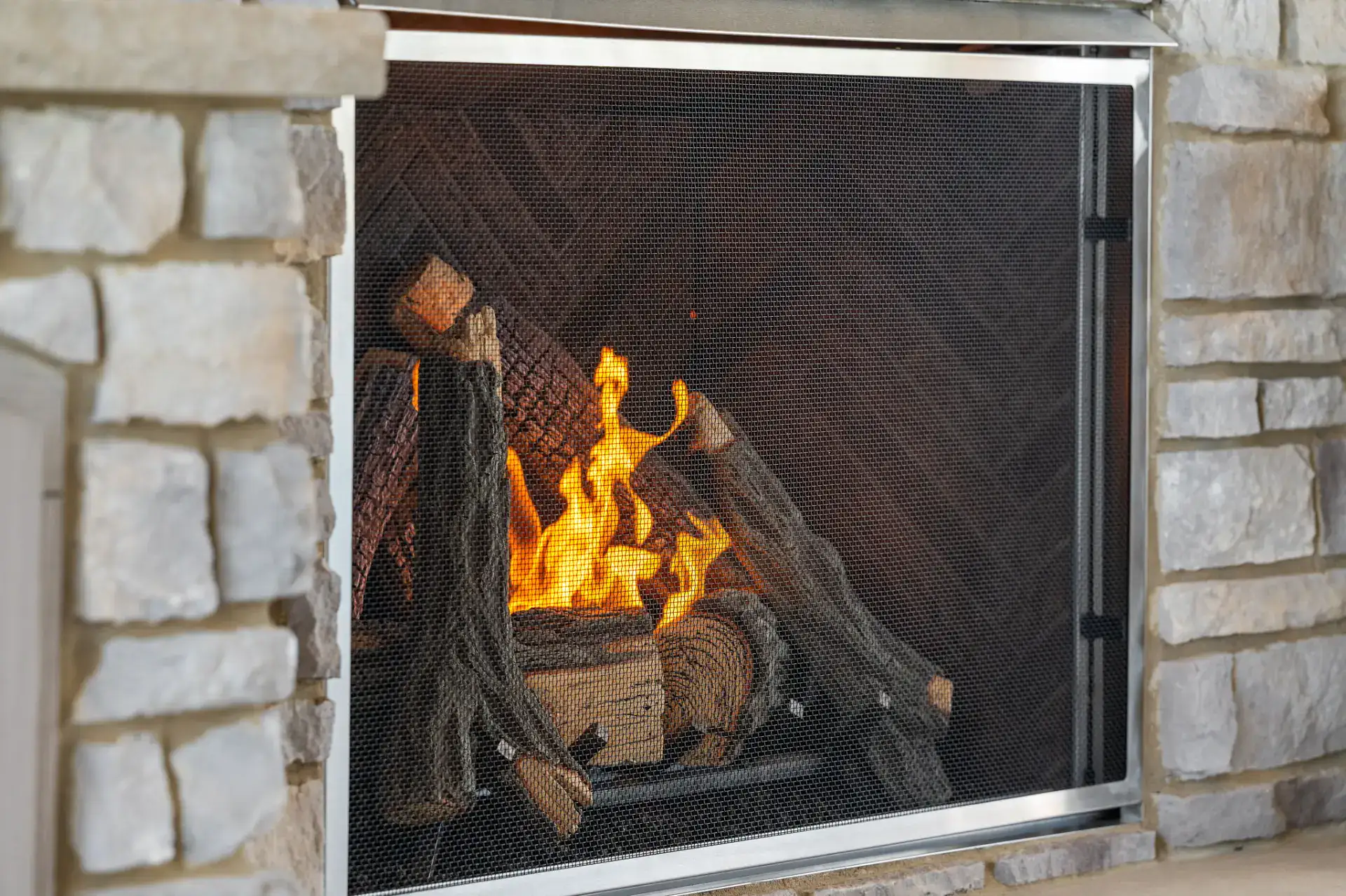 Outdoor stone fireplace with fire lit in Medina, Ohio by TAB Property Enhancement