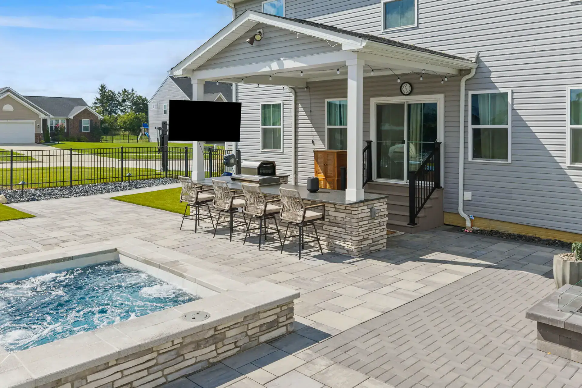 Outdoor kitchen bar seating beside a stone spa surround in Medina, Ohio by TAB Property Enhancement
