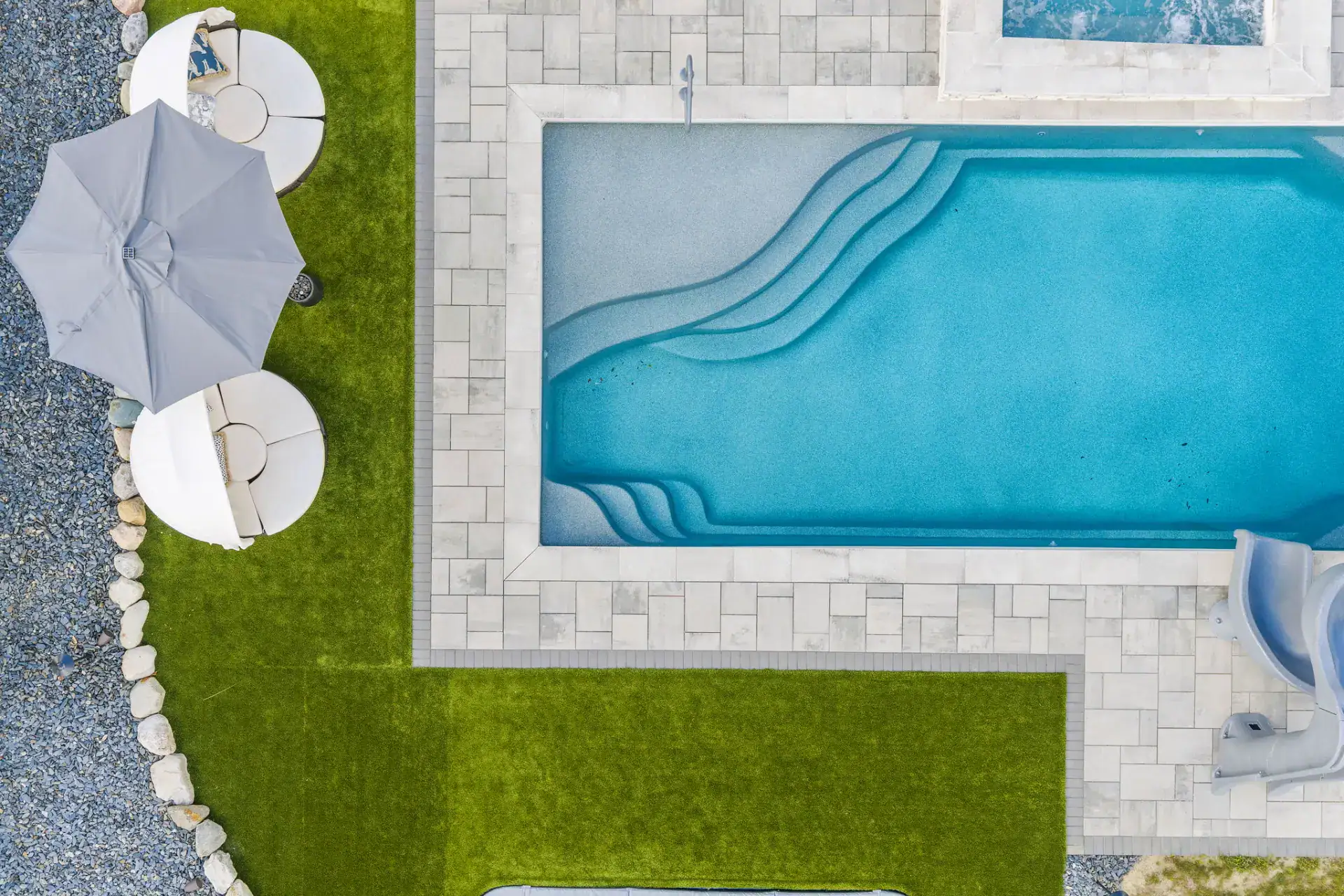 Large-format paver pool deck meeting artificial turf in Medina, Ohio by TAB Property Enhancement
