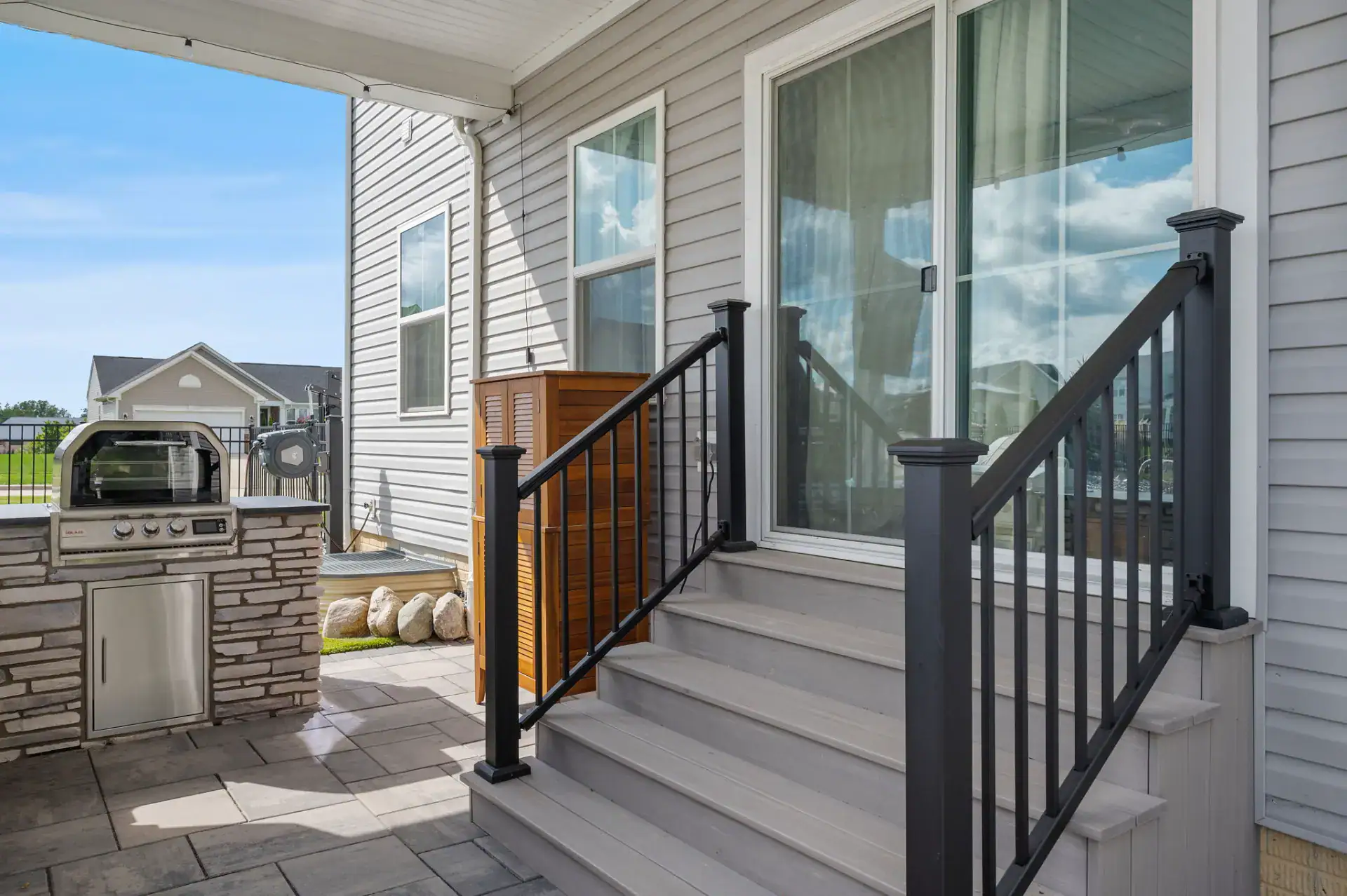 Composite steps and railing beside an outdoor kitchen grill in Medina, Ohio by TAB Property Enhancement
